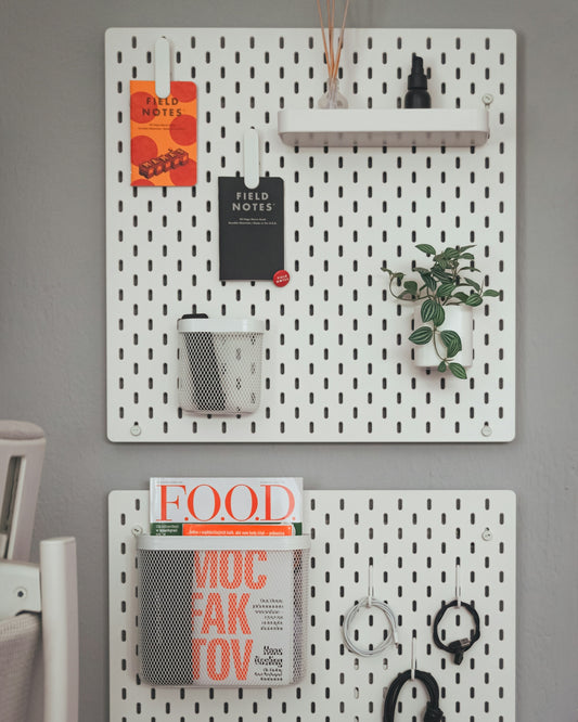 A couple of white pegboards mounted to the side of a wall