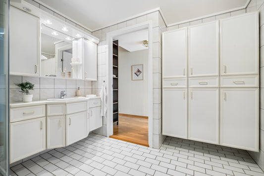 A large bathroom with white cabinets and tile flooring