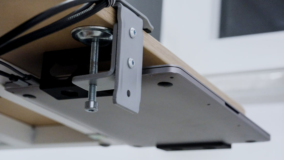 Laptop clamped under a wooden desk with cables.