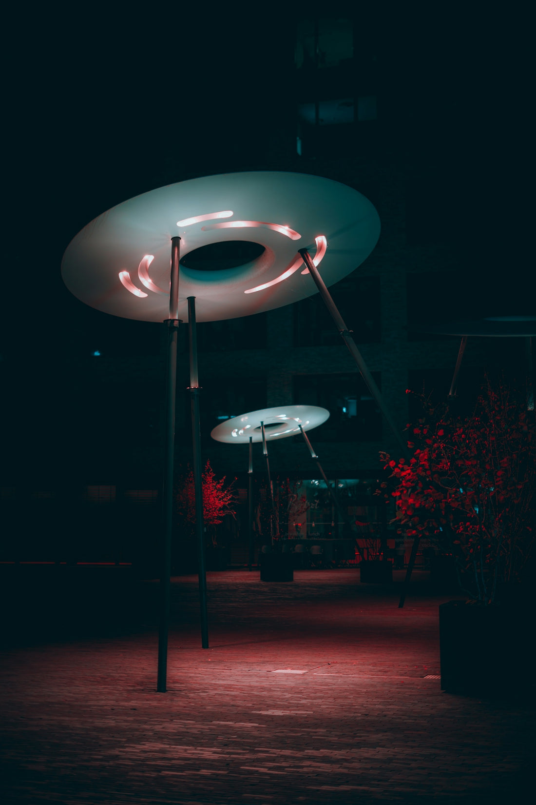 Modern disc-shaped lights illuminate a dark park at night.