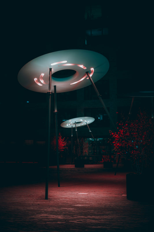 Modern disc-shaped lights illuminate a dark park at night.