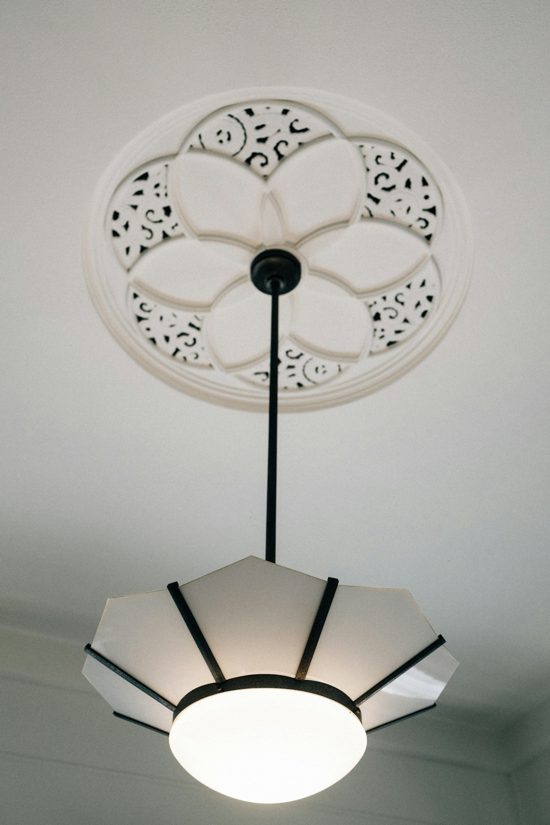 A decorative ceiling medallion with a modern pendant light.