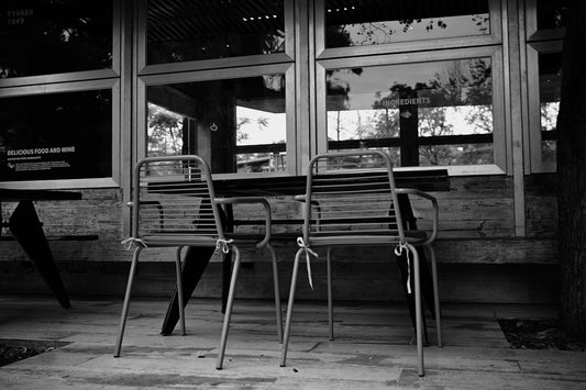 Two chairs and table on patio with large windows behind