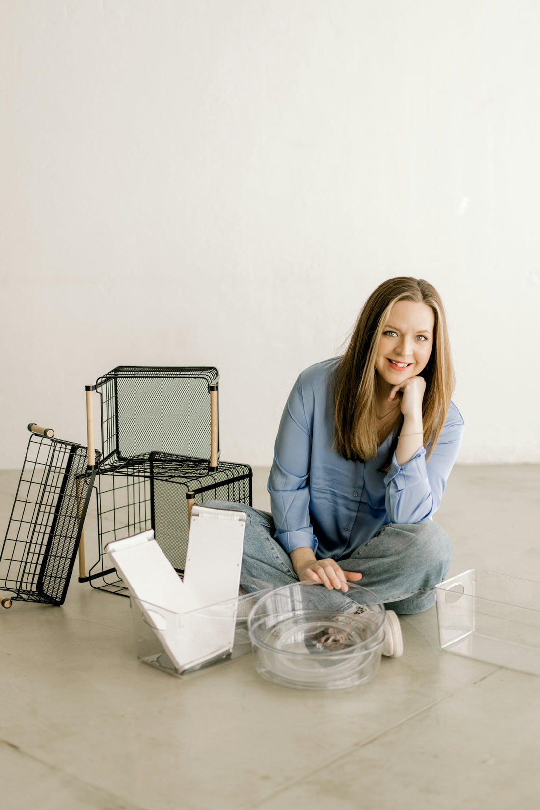 Smiling woman on floor surrounded by home organization products.