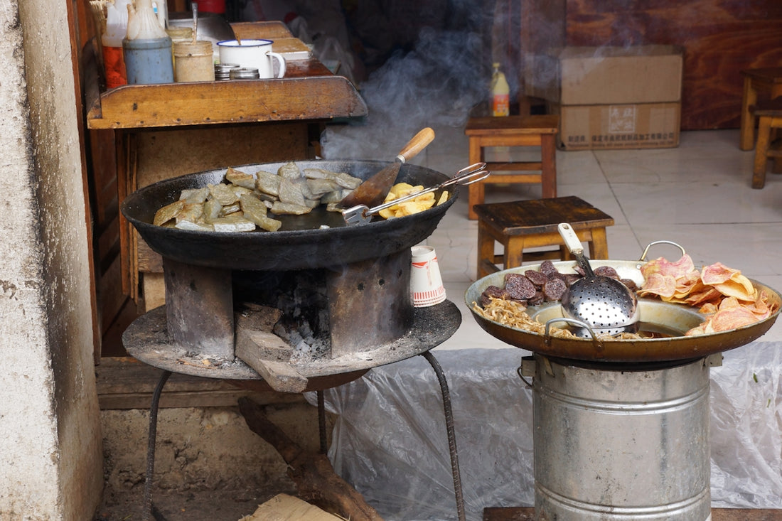 Street food cooking over traditional stoves with various dishes.